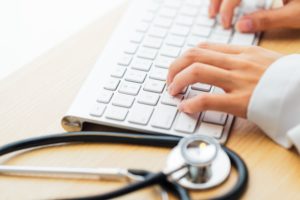 Doctor typing keyboard with stethoscope